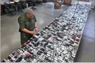  ?? AP FILE PHOTO BY RICH PEDRONCELL­I ?? In this 2009 photo, Correction­al Officer Jose Sandoval inspects one of the more than 2,000 cell phones confiscate­d from inmates at California State Prison, Solano in Vacaville.