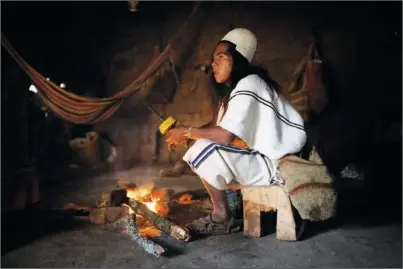  ?? ?? Mariano, a 30-year-old Arhuaco Indigenous man, sits by the fire Jan. 17 at his home in Nabusimake. Mariano is a “Mamo,” or spiritual leader, that keeps his people’s ancient knowledge.