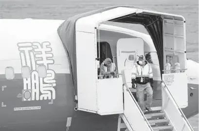  ?? TED S. WARREN AP ?? Boeing workers stand near an entry door to a 737 Max airplane owned by China-based Lucky Air, in Renton, Wash. China isn’t ready to join the United States in approving Boeing’s 737 Max to return to flying.