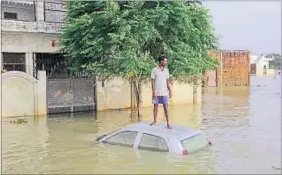  ?? AP PHOTO ?? A man stands on top of his submerged car as he waits for a boat next to his house in Allahabad, Uttar Pradesh, on Saturday.