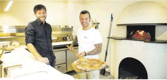  ?? Joan Cortadella­s ?? Antonello Belardo y Alessandro Signore, con una pala y una pizza, en el Nap Molino.