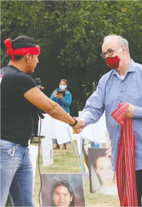  ?? ARTHUR WHITE-CRUMMEY / POSTMEDIA NEWS FILES ?? Chris Merasty, who walked with Tristen Durocher from northern Saskatchew­an, hands Justice Graeme Mitchell a Métis sash outside Durocher's teepee on Sept. 13.