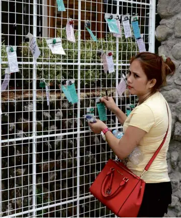  ?? DELFIN T. MALLARI JR./INQUIRER SOUTHERN LUZON ?? LOCKED PRAYERS A devotee inspects her padlock at the “prayer lock” station, the latest spiritual attraction at Kamay ni Hesus Shrine in Lucban, Quezon. Up to 6 million pilgrims are expected to visit the place during Holy Week.