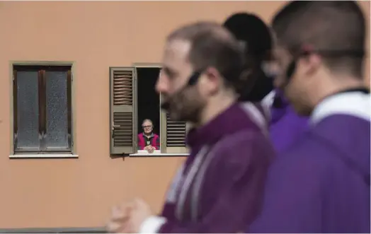  ?? FABI/AFP TIZIANA ?? En Roma, un sacerdote oficia una misa en una plaza pública. Desde las ventanas y los balcones, feligreses en cuarentena siguen la ceremonia.