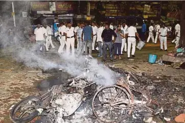  ?? AFP PIC ?? Police standing next to burning debris on a street following clashes by rival groups during a campaign rally held by Amit Shah, president of the ruling Bharatiya Janata Party, in Kolkata on Tuesday.