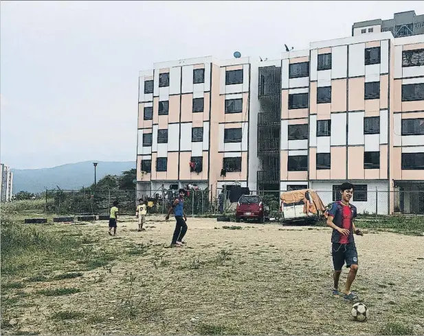  ??  ?? Unos chavales juegan al fútbol en un descampado junto a unos bloques de viviendas de Ciudad Caribia