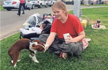  ?? TERRY CHEA, AP ?? Marcella Mooney plays with her dog as her daughter sleeps in a car seat Monday at the Silver Dollar Fairground­s in Chico, Calif. Mooney’s family had to evacuate Oroville.