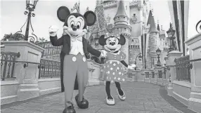  ?? DISNEY ?? Mickey Mouse and Minnie Mouse in front of the Magic Kingdom castle.