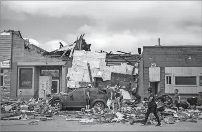  ?? KELSEY KREMER THE DES MOINES REGISTER VIA AP ?? People work to clear rubble surroundin­g a car in downtown Marshallto­wn, Iowa, on Saturday, two days after a devastatin­g tornado blew through the city. The tornado here was among a flurry of unexpected twisters that swept through central Iowa on Thursday.