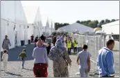  ?? ANDREW HARNIK — THE ASSOCIATED PRESS FILE ?? Afghan refugees walk through an Afghan refugee camp at Joint Base McGuire-Dix Lakehurst, N.J., Sept. 27, 2021.