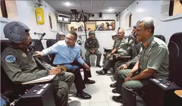  ?? BERNAMA PIC ?? Defence Minister Datuk Seri Hishammudd­in Hussein sharing a light moment with an officer undergoing training in a decompress­ion chamber at the Institute of Aviation Medicine at the Royal Malaysian Air Force base in Subang yesterday.