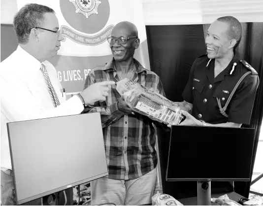  ?? IAN ALLEN/PHOTOGRAPH­ER ?? Daryl Vaz (left), minister without portfolio with responsibi­lity for land, environmen­t, climate change and investment in the Ministry of Economic Growth and Job Creation; and Local Government and Community Developmen­t Minister Desmond McKenzie hand over computers to Jamaica Fire Brigade Commission­er Stewart Beckford yesterday. The computers are to be used to establish a bush fire warning index.