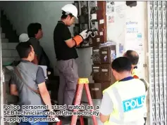  ??  ?? Police personnel stand watch as a SEB technician cuts off the electricit­y supply to a premise.