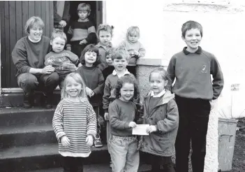  ?? 01_B09twe02 ?? On the steps of the Kilmory Hall last Monday, five-year-old Raiann Sim and 11-year-old Sandy McMaster, respective­ly the youngest and oldest pupils of Kilmory Primary, present a cheque for £140 to four-year-old Bobbi Adamson, the oldest member of the Kilmory Playgroup. The schoolchil­dren raised the money with a sponsored silence.