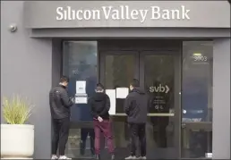  ?? AP photo ?? People look at signs posted outside of an entrance to Silicon Valley Bank in Santa Clara, Calif., on Friday. From winemakers in California to startups across the Atlantic Ocean, companies are scrambling to figure out how to manage their finances after their bank, Silicon Valley Bank, suddenly shut down on Friday.