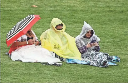  ?? ROB SCHUMACHER/THE REPUBLIC ?? Fans sitting in the outfield cover up as rain falls Monday during the spring training game between the Arizona Diamondbac­ks and the Cincinnati Reds at Salt River Fields in Scottsdale.