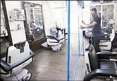  ?? MICHAEL VARCAS ?? A barber of the Gupitan Barbershop in Quezon City puts up plastic separators between chairs yesterday ahead of the resumption of grooming services in Metro Manila.