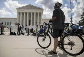  ?? Andrew Harnik, The Associated Press ?? A bicyclist watches as journalist­s gather Thursday at the Supreme Court building in Washington.