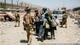  ??  ?? Italian coalition forces assist and escort evacuees for onward processing during an evacuation at Kabul airport