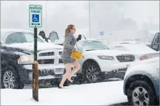  ?? Associated Press photo ?? A shopper dashes to her car during a blizzard after shopping Sunday at the Walmart in Roeland Park, Kan. The National Weather Service issued a blizzard warning for parts of Nebraska, Kansas, Missouri and Iowa.