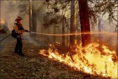  ?? ?? Captain Gabe Barrio sprays water on the Mosquito Fire burning along Michigan Bluff Rd. in unincorpor­ated Placer County on Wednesday.