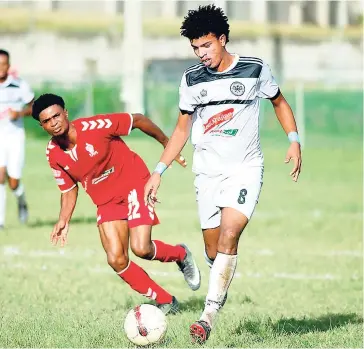  ?? RICARDO MAKYN ?? UWI FC’s Patrick Brown looking on while Cavalier player Leonardo Rankine (right) dribbles away with the ball, in their Red Stripe Premier League encounter at the UWI Mona Bowl on Sunday, December 2, 2018.