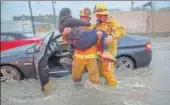 ?? AFP ?? Firefighte­rs rescue a woman after her car was caught in street flooding in California’s Sun Valley on Friday. The strongest storm to hit the US state in six years has triggered flooding, mudslides and power outages and has resulted in the death of four...