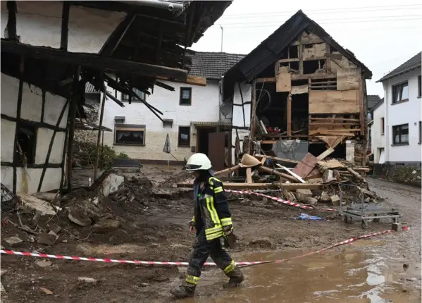  ?? AFP ?? Una bombera caminó, este sábado, frente a casas gravemente dañadas por las inundacion­es, en Schuld, en el oeste de Alemania.