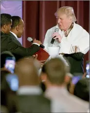  ?? AP/EVAN VUCCI ?? Republican presidenti­al candidate Donald Trump wears a prayer shawl Saturday as he is presented with a gift during a church service at Great Faith Ministries in Detroit.