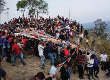  ?? ?? People carry the cross Monday after taking it down from the hilltop.