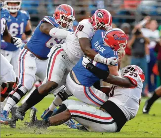  ?? CURTIS COMPTON / CCOMPTON@AJC.COM ?? Florida quarterbac­k Kyle Trask gets wrapped up by Georgia defensive linemen Jordan Davis (right) and Malik Herring during the third quarter.