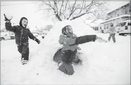  ?? CATERINA/SOUTH BEND TRIBUNE] [MICHAEL ?? Chase Vicen, 7, sneaks up on Sara Tapia, 8, with a snowball Friday as she gets out of an igloo they made while playing in South Bend, Ind.