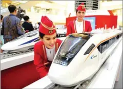  ?? BAY ISMOYO/AFP ?? Indonesian models look at scale models of Chinese-made bullet trains on exhibition at a shopping mall in Jakarta on August 13, 2015.