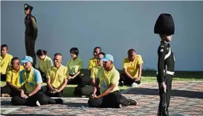  ?? — AFP ?? Smooth operators: A soldier standing beside volunteers during a rehearsal for the royal coronation in Bangkok.