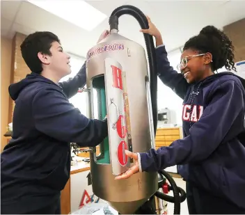  ?? DAN JANISSE ?? Lucas Makhlouf and Alexa Kenneth-Ogah, members of the Cougarboti­cs 6.0 team from Cardinal Carter Catholic Middle School in Leamington, work with their micro-gravity shower unit.