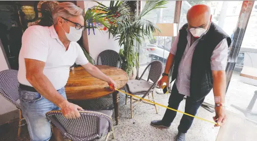  ?? ERIC GAILLARD/REUTERS ?? As we relearn how to share space, we’ll probably find that what was once polite may be rude. Above, restaurant staffers in France measure the distance between tables.