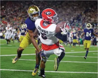  ?? THE ASSOCIATED PRESS ?? Georgia wide receiver Terry Godwin makes a catch against Notre Dame cornerback Julian Love for a touchdown during the first half of Saturday’s game in South Bend, Ind. Georgia won 20-19.