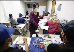  ?? ?? Center for Pan Asian Community Services teacher Annie Suen hands out assessment­s to students last month. Though enrollment at CPACS’ program has rebounded from its 2020 low, it is still 35% lower than pre-pandemic levels.