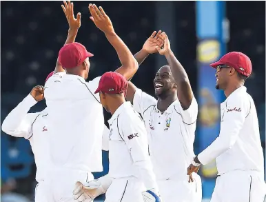  ?? FILE ?? Windies pacer Kemar Roach (second right) celebrates with teammates after taking a wicket on the second day of the first Test against Sri Lanka at Queen’s Park Oval in Trinidad on June 7.