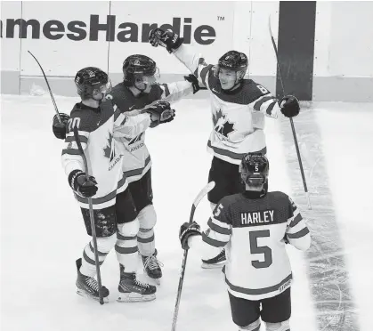  ?? GREG SOUTHAM • POSTMEDIA NEWS ?? Jordan Spence, clockwise from top right, receives congratula­tions from teammates Thomas Harley, Dawson Mercer and Ryan Suzuki after scoring the opening goal against Slovakia at the world junior championsh­ip in Edmonton.