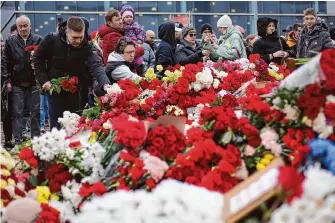  ?? Vitaly Smolnikov/Associated Press ?? People place flowers and toys at the fence next to Crocus City Hall on Sunday, a day of national mourning. Suspects accused of opening fire on concertgoe­rs arrived in court Sunday night.