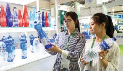  ??  ?? Visitors check out drinking water products during a beverage exhibition in Beijing.