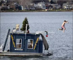  ?? BEN GARVER — THE BERKSHIRE EAGLE VIA AP ?? In this file photo, a man jumps into Pontoosuc Lake in Pittsfield, Mass. The New England lake is typically frozen in December, but unusually warm temperatur­es have kept the water open. On Thursday the National Weather Service forecasted a warmer than normal 2018-2019 winter for the northern and western three-quarters of the U.S.