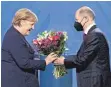  ?? FOTO: J. MACDOUGALL/AFP ?? Ein Dankeschön für die Vorgängeri­n: Angela Merkel erhält von Kanzler Olaf Scholz Blumen.