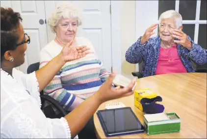  ?? Erik Trautmann / Hearst Connecticu­t Media ?? ElderHouse employee April Mattison reads trivia questions to clients, including Barbara Johnson and Viola Fretina, as they participat­e in activity time Thursday at the facility in Norwalk. ElderHouse is a nonprofit day care center that offers medical and social services during the day. Below, Henrietta DeLarge colors a picture.