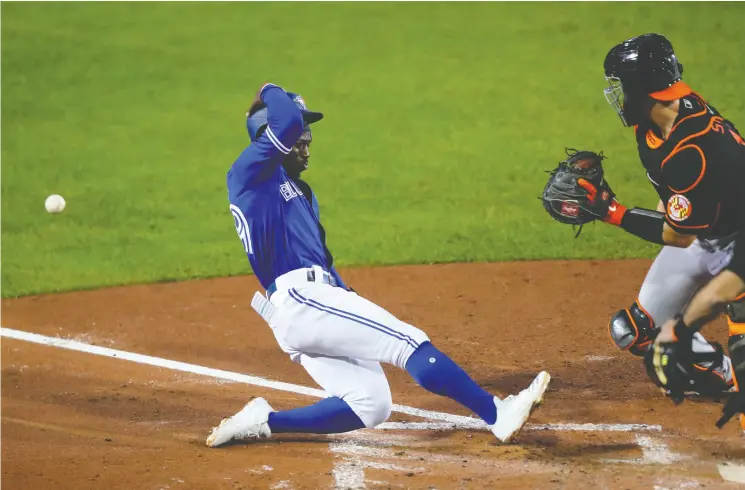  ?? Timothy T Ludwig / Gett y Imag es ?? Toronto’s Jonathan Davis beats the throw to home in the Blue Jays’ 10-5 Friday night win over the Baltimore Orioles at Sahlen Field. Go to nationalpo­st.com for more on the game.