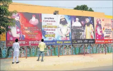  ?? HT PHOTOS ?? WRITING ON THE WALL: Followers put up hoardings outside the sect headquarte­rs in Sirsa, greeting the dera chief on his 51st birthday on August 15.