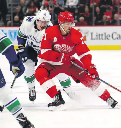  ?? GREGORY SHAMUS/GETTY IMAGES ?? Canucks forward Tim Schaller keeps a close watch on Detroit counterpar­t Dylan Larkin, as the Red Wing tries to control the puck on Tuesday at Little Caesars Arena. The 22-year-old Red Wings centreman potted the game-winning goal in a shootout.