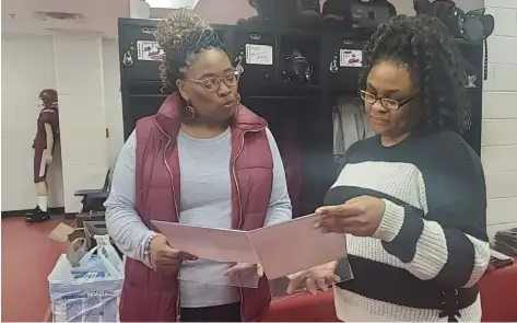  ?? (Pine Bluff Commercial/Suzi Parker) ?? Zebra moms Trammell Howell and Daisha Thompson look at photos given to seniors in their gift bags provided by the Zebras’ “Mom Squad.”