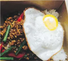  ??  ?? Pad ga pao, or chicken over rice, has darkly marinated ground chicken and an oozy-yolked fried egg served over the rice.